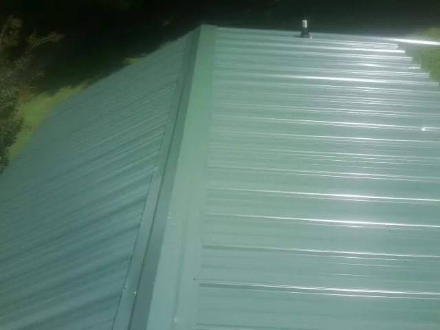 New green metal panels meeting at the ridge of a roof — Flat Roof Repair work by our crew in Palisades