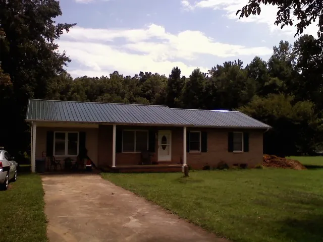 Dark green metal roof on a brick ranch with a covered porch in Palisades