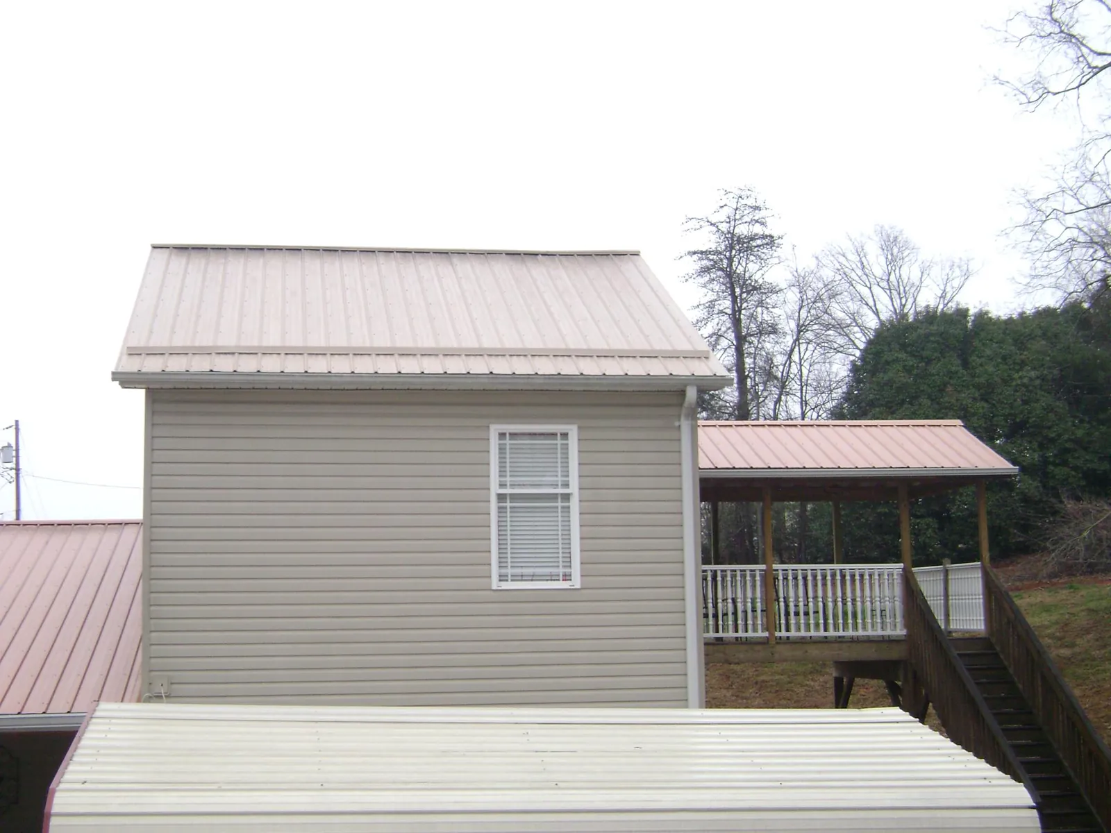 Tan metal roofs on a two story addition and attached porch, from a Roof Replacement job in Palisades